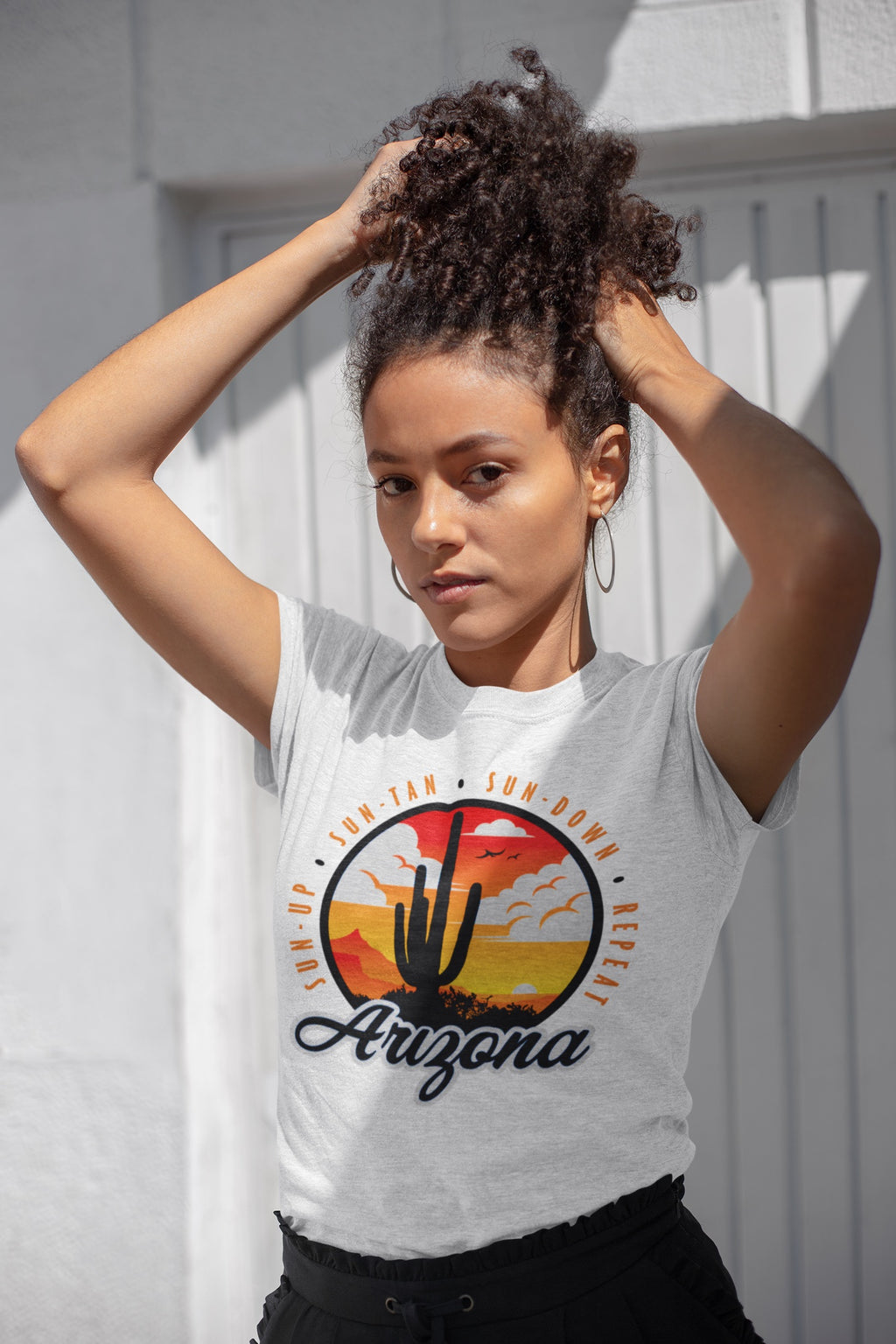 A woman wearing a super soft white t-shirt with an Arizona Sunset Design with the saying Sun Up, Sun Tan,  Sun Down, Repeat 